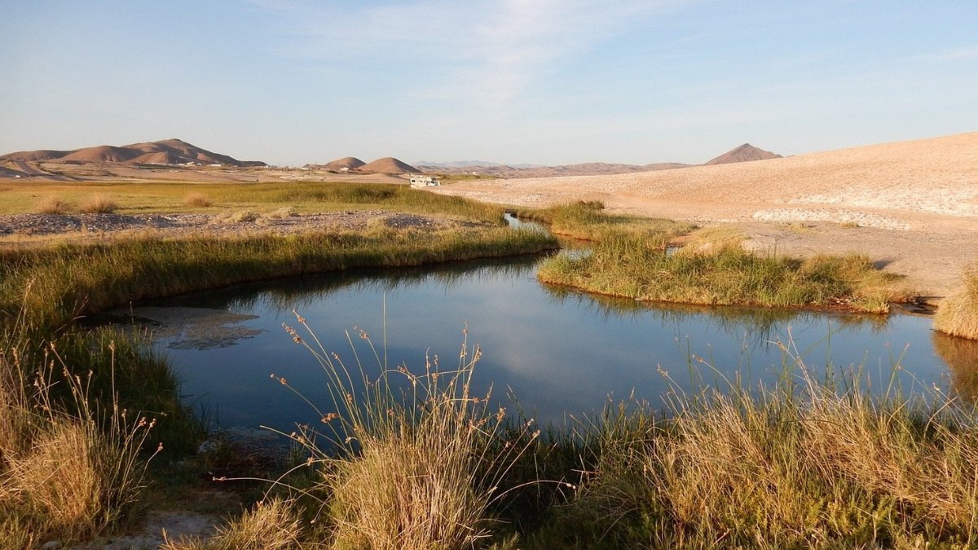 Hot spring pool glowing at golden hour below the desert hills of the Tecopa Valley